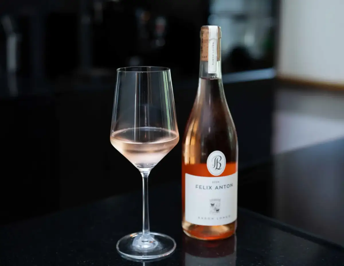 Glas Roséwein und Flasche auf dunklem Tresen