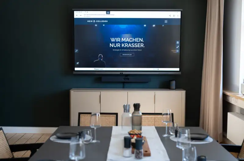 Bildschirm mit der Hein & Kollegen Website über gedeckter Tafel im UnternehmerQuartier
