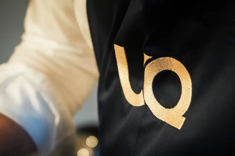 UQ-Schürze mit goldener Stickerei im UnternehmerQuartier